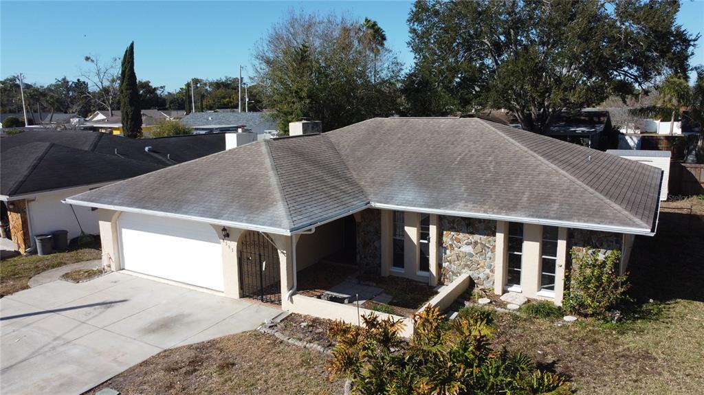 An aerial view of a single-story house with a stone facade and a shingled roof — 8533 VIVA VIA DRIVE, HUDSON, FL