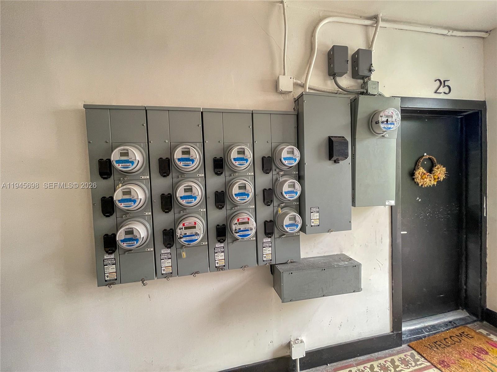 A wall-mounted electrical meter bank is located next to a door marked with number 25 — 36 NE 65th St, Miami FL 33138, MIAMI, FL