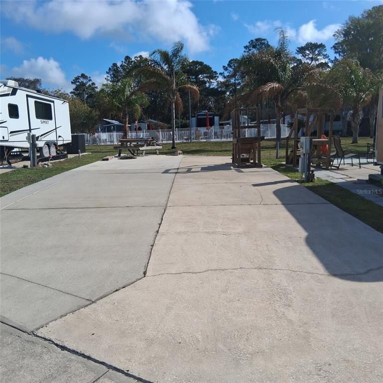 A concrete RV pad with a picnic table and wooden structures under palm trees — 1074 FRONT STREET UNIT 51, WELAKA, FL