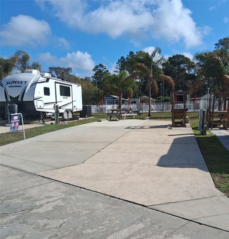A concrete RV pad features a parked travel trailer, a picnic table, and palm trees — 1074 FRONT STREET UNIT 51, WELAKA, FL