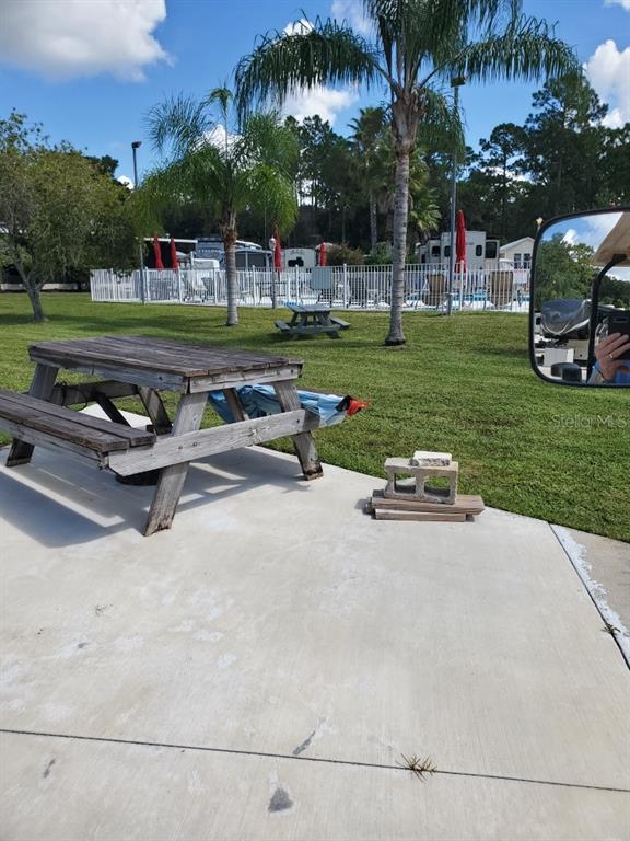 A wooden picnic table sits on a concrete patio near a swimming pool area — 1074 FRONT STREET UNIT 51, WELAKA, FL