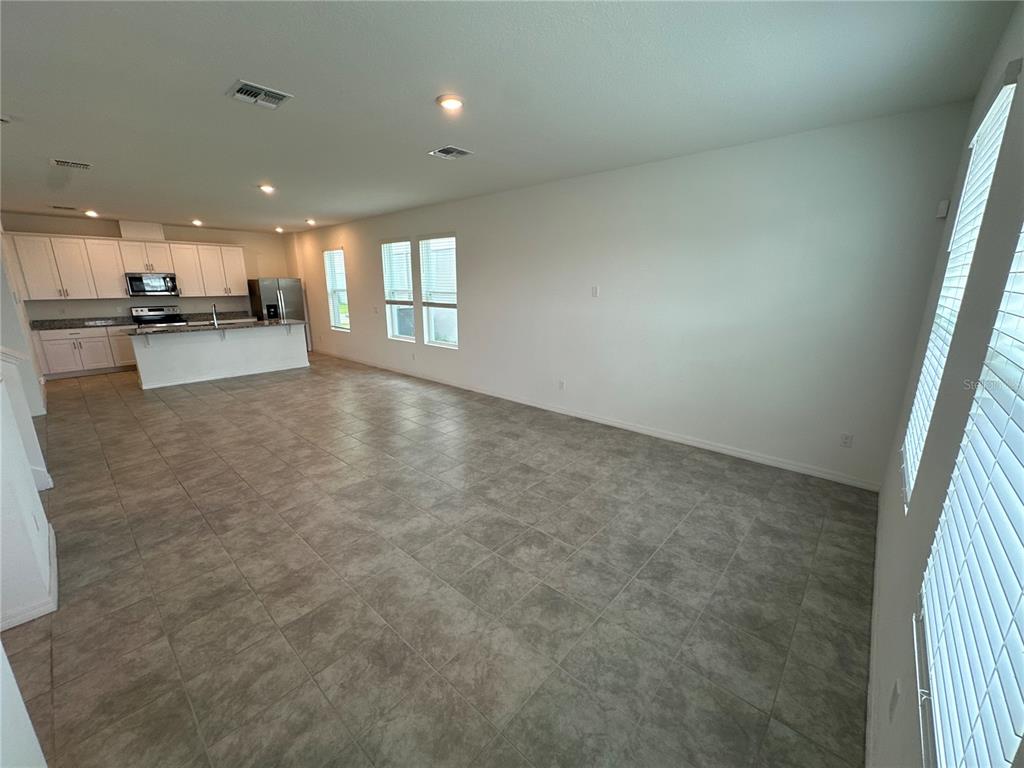 An open-concept kitchen and living area features tile flooring, white cabinets, and large windows — 4724 HOMESTEAD TRAIL, ST CLOUD, FL