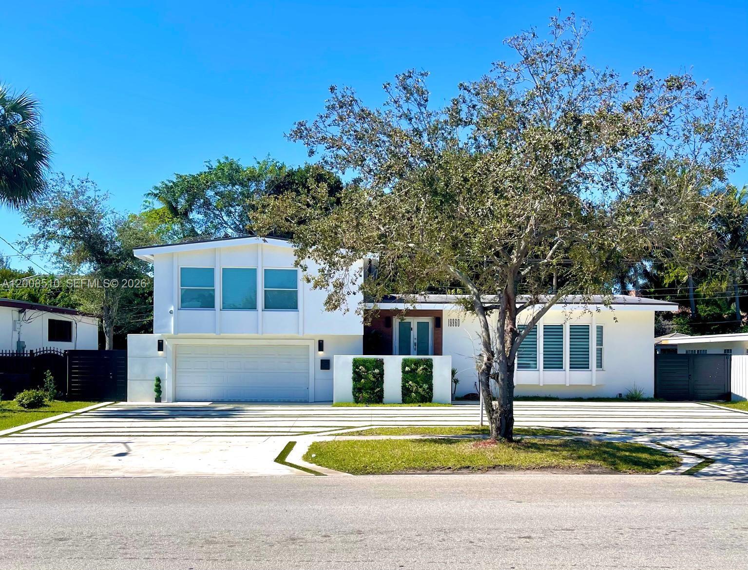 A two-story white house with a two-car garage and a large tree in front — 19960 Highland Lakes Blvd, Miami FL 33179, MIAMI, FL