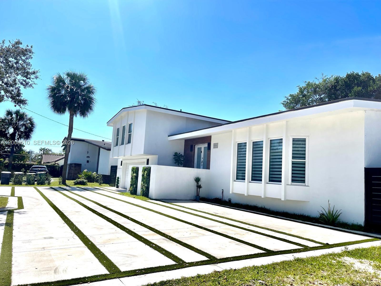 A modern white house features a large driveway with concrete pavers and artificial grass strips — 19960 Highland Lakes Blvd, Miami FL 33179, MIAMI, FL