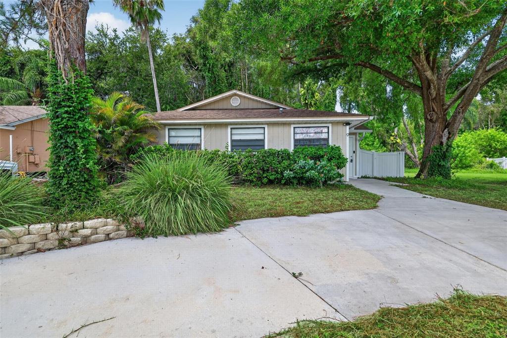 A single-story house with tan siding, a brown roof, and a concrete driveway — 9 FRESHWATER DRIVE, PALM HARBOR, FL
