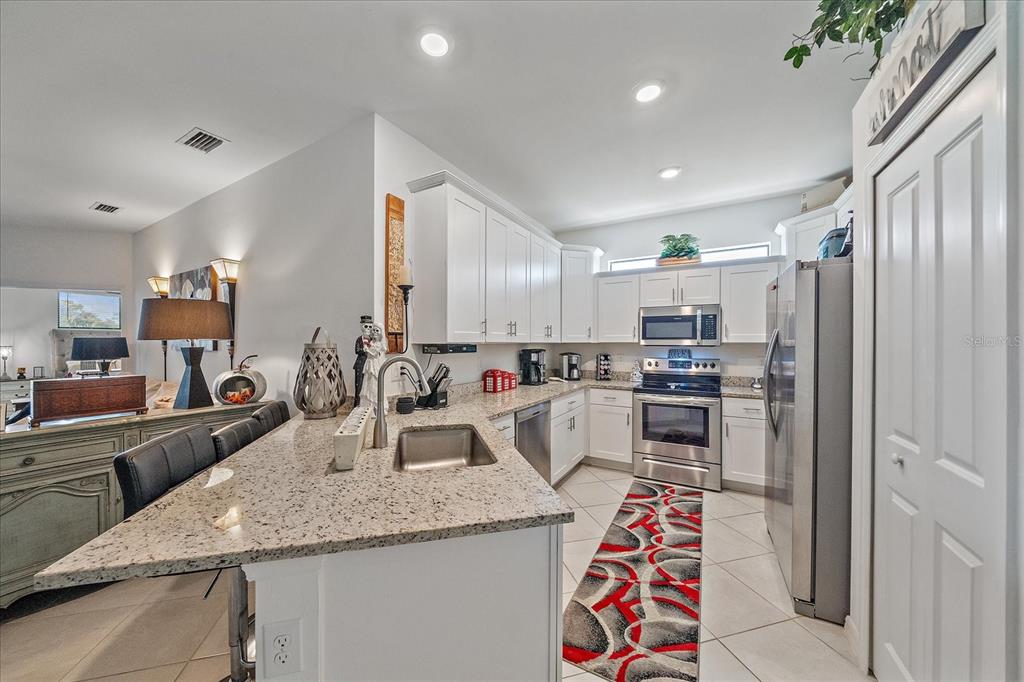 A kitchen features white cabinets, granite countertops, stainless steel appliances, and a tiled floor — 2016 BONITO WAY, PORT CHARLOTTE, FL