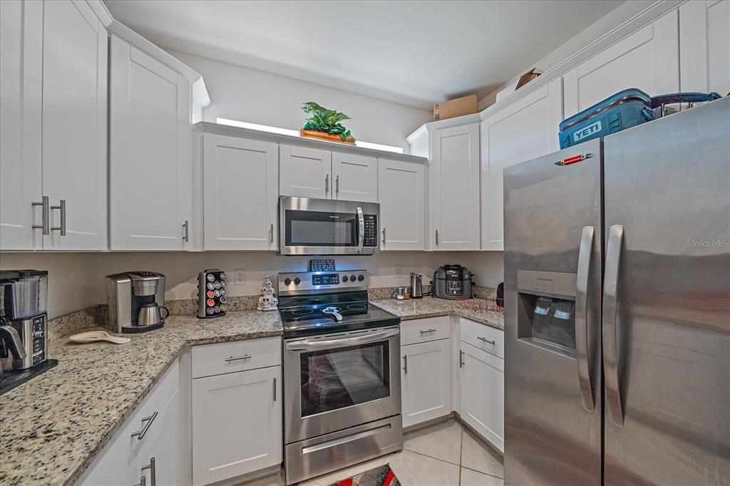 A kitchen features white cabinets, granite countertops, and stainless steel appliances — 2016 BONITO WAY, PORT CHARLOTTE, FL