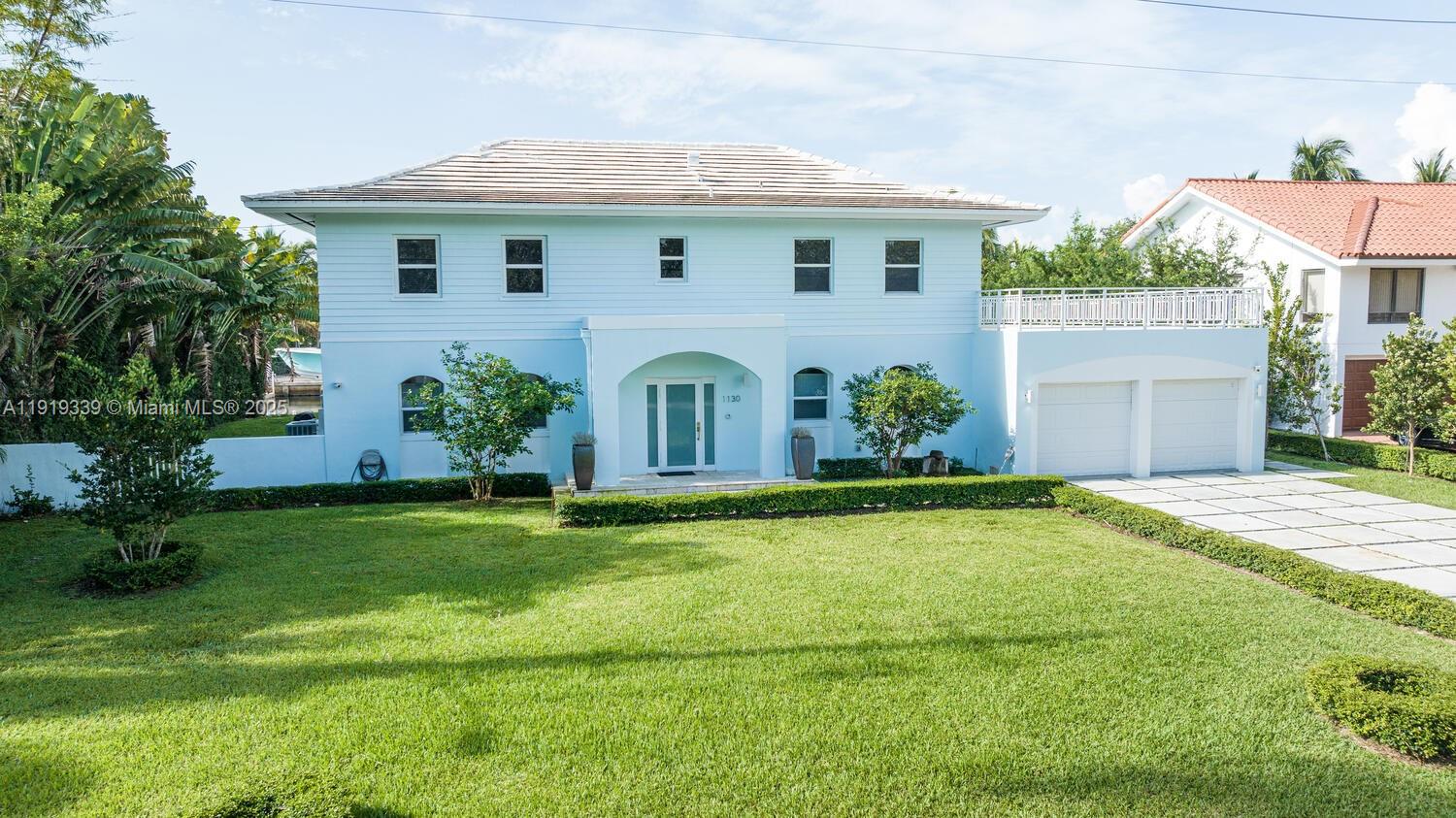 A light blue two-story house features a front lawn, a driveway, and a two-car garage — 1130 Lugo Ave, Coral Gables FL 33156, CORAL GABLES, FL