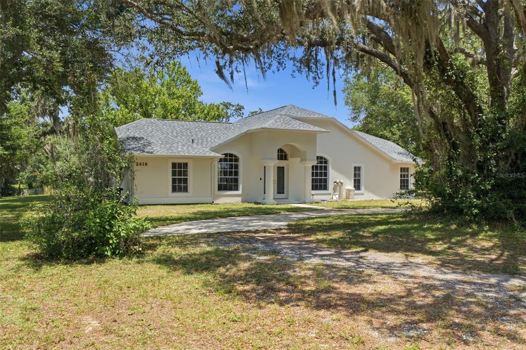 A single-story house with a light-colored stucco exterior and a gray shingled roof — 2419 E STAGE COACH TRAIL, INVERNESS, FL