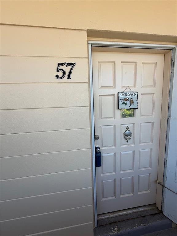 A beige exterior wall with the number 57 next to a white paneled front door — 2383 NETHERLANDS DRIVE UNIT 57, CLEARWATER, FL
