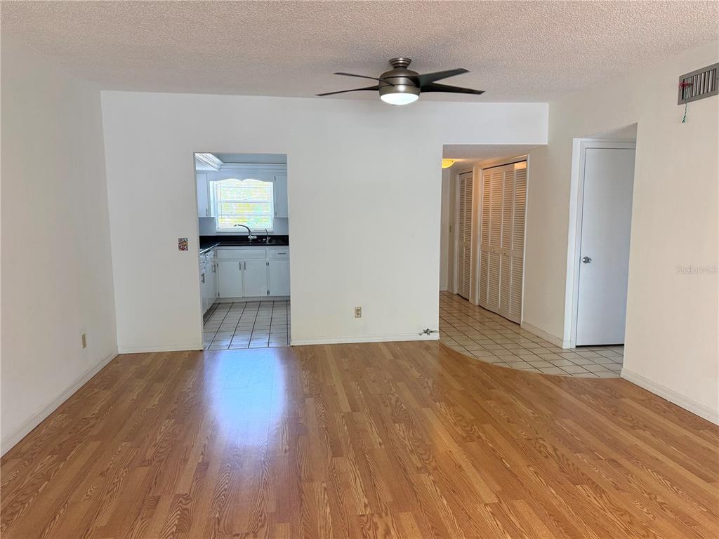 An open living area with hardwood flooring, a ceiling fan, and a view of the kitchen — 2383 NETHERLANDS DRIVE UNIT 57, CLEARWATER, FL