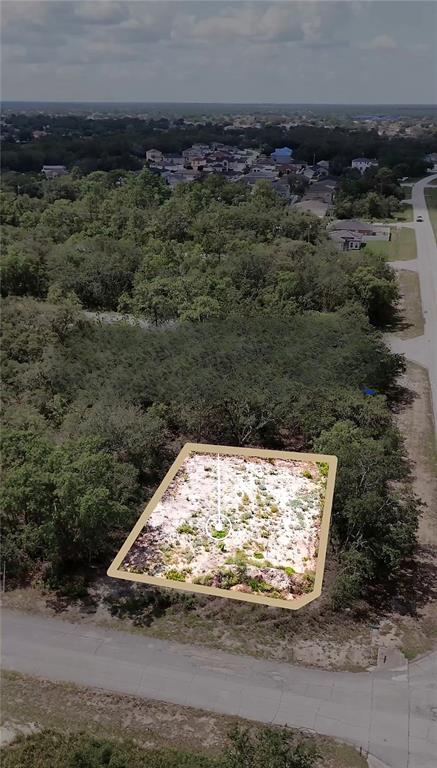 An aerial view shows a vacant, partially cleared residential lot surrounded by trees and roads — 449 NAPLES COURT, KISSIMMEE, FL