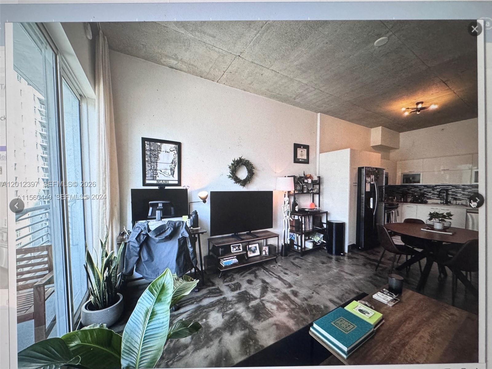 An open-concept living area features a concrete ceiling, stained concrete floors, and an adjacent kitchen — 133 NE 2nd Ave # 2003, Miami FL 33132, MIAMI, FL