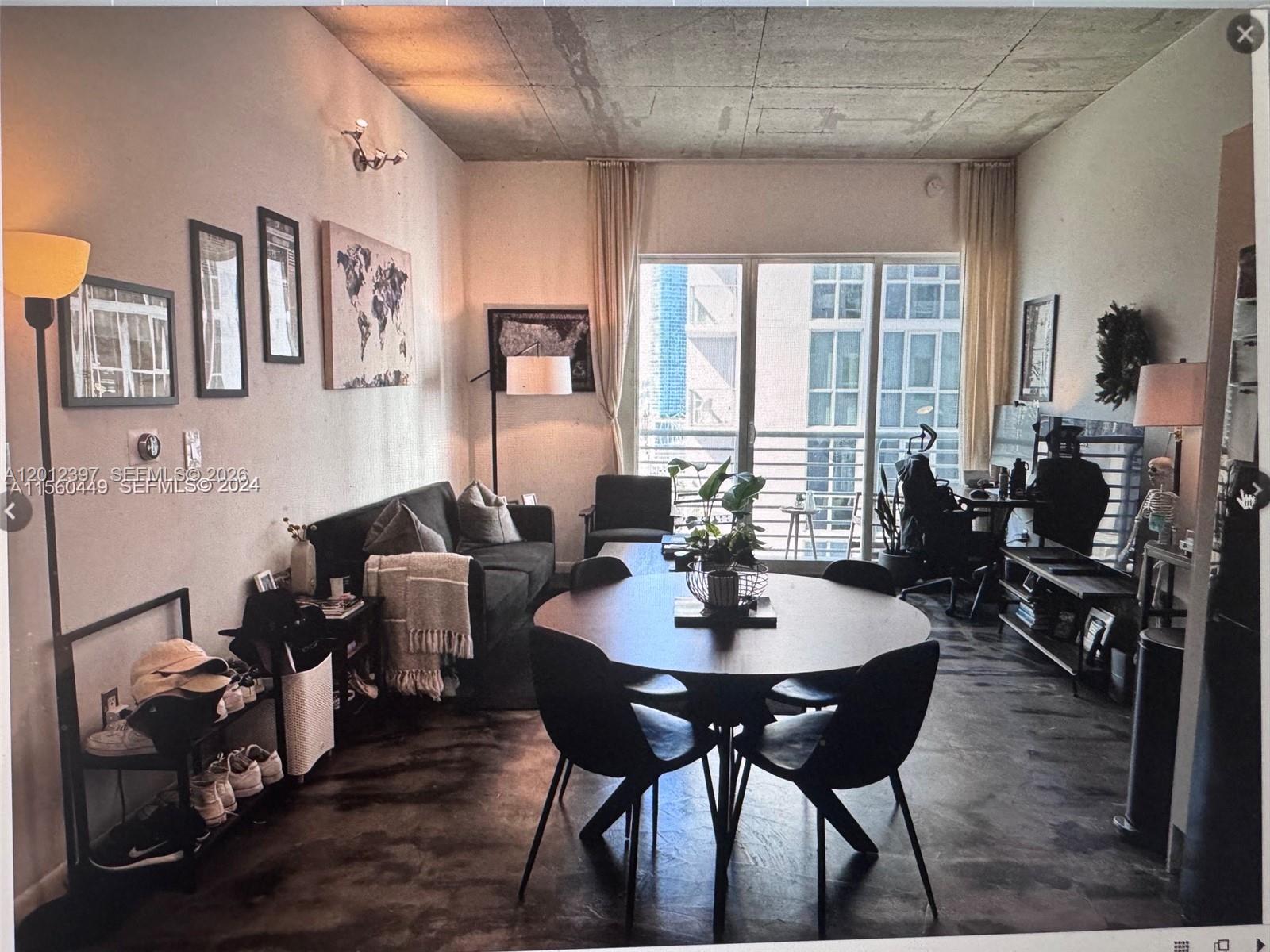 A living and dining area features a concrete ceiling, dark flooring, and a balcony view — 133 NE 2nd Ave # 2003, Miami FL 33132, MIAMI, FL