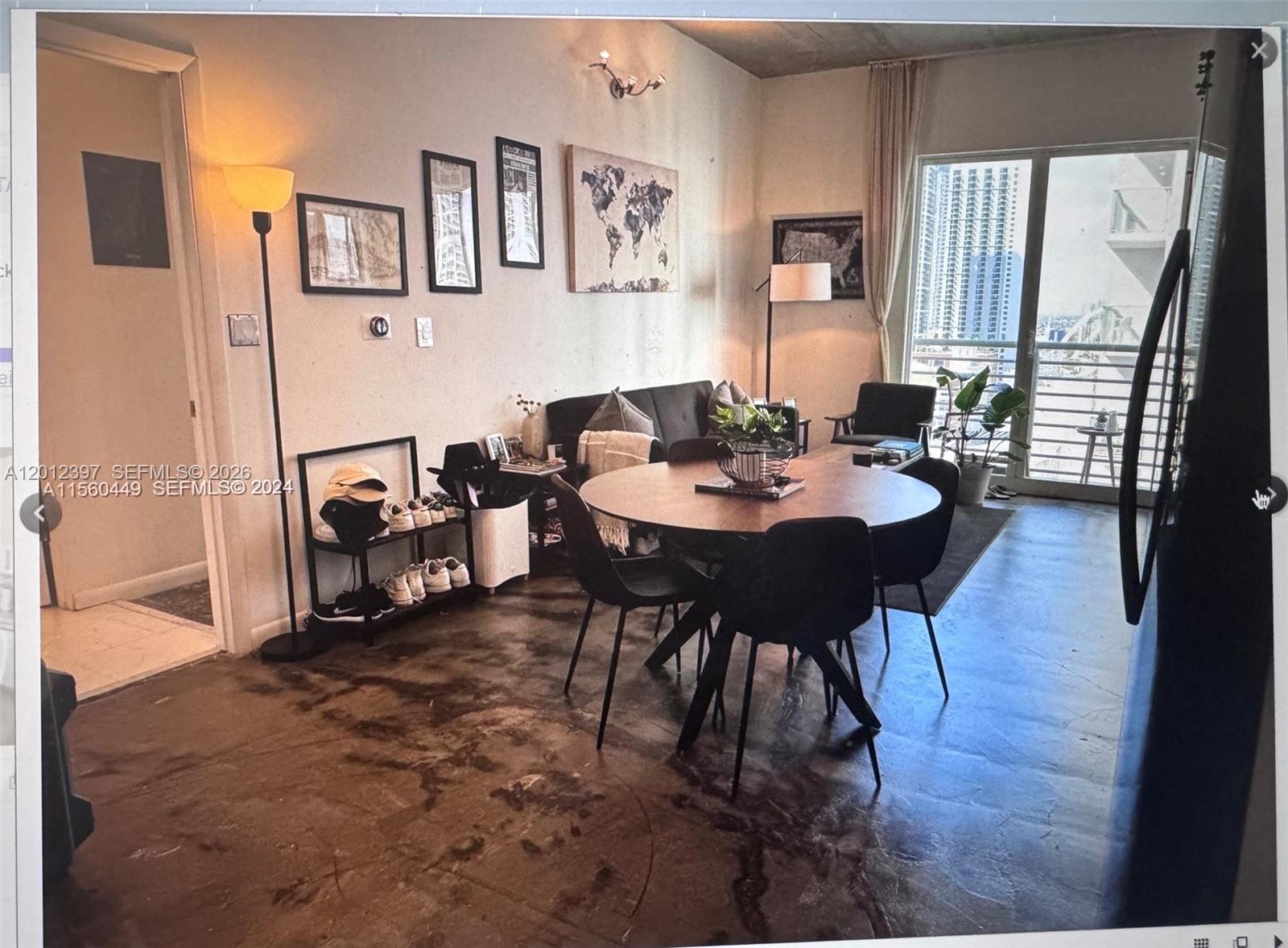 A dining and living area features a round table, dark concrete floors, and balcony access — 133 NE 2nd Ave # 2003, Miami FL 33132, MIAMI, FL
