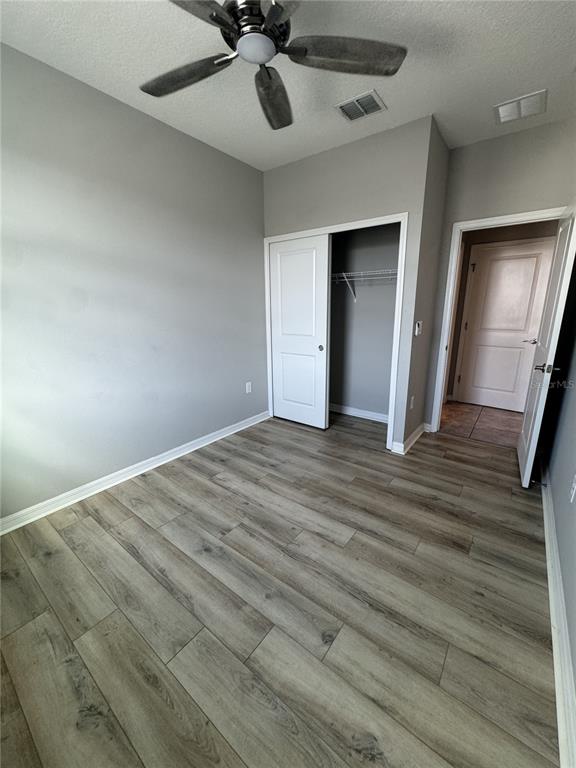 This bedroom features light gray walls, wood-look flooring, a ceiling fan, and a closet — 16042 MICELLI DRIVE, WINTER GARDEN, FL
