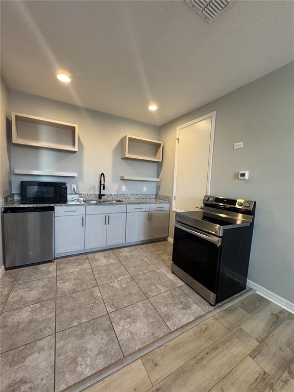 A kitchen features light gray cabinets, granite countertops, stainless steel appliances, and tile flooring — 16042 MICELLI DRIVE, WINTER GARDEN, FL