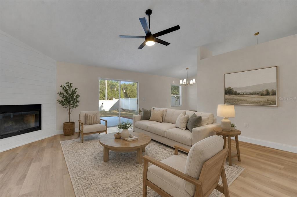 A living room features a fireplace, a beige sofa, two armchairs, and a ceiling fan — 3311 QUEENS COVE LOOP, WINTER HAVEN, FL
