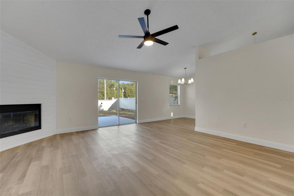 A living room features light wood-look flooring, a white shiplap fireplace, and a ceiling fan — 3311 QUEENS COVE LOOP, WINTER HAVEN, FL