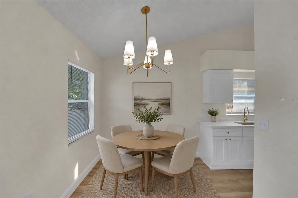 A dining area features a round wooden table, four chairs, and a modern chandelier — 3311 QUEENS COVE LOOP, WINTER HAVEN, FL