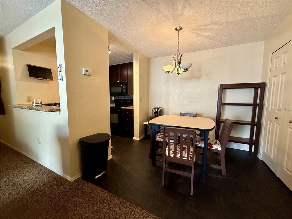 A dining area with a table, chairs, and a bookshelf next to a kitchen pass-through — 3705 SW 27TH STREET UNIT 525, GAINESVILLE, FL