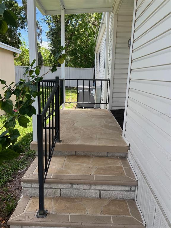 A set of concrete steps with stone-patterned treads leads to a covered porch with railings — 29250 US HIGHWAY 19 N UNIT 12, CLEARWATER, FL
