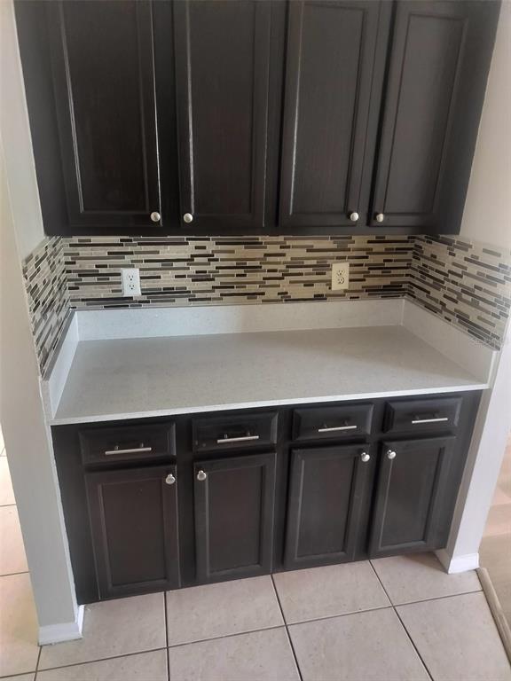 A kitchen wet bar features dark wood cabinets, a light countertop, and a mosaic tile backsplash — 6730 BRITTANY CHASE COURT, ORLANDO, FL