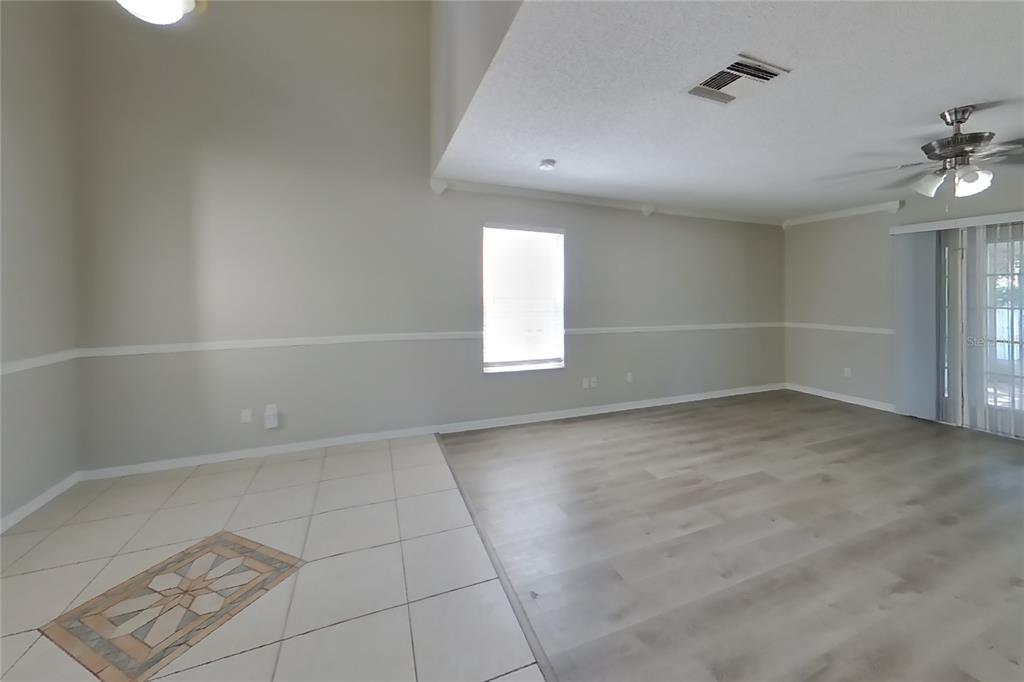An open living area features light-colored tile flooring, wood-look laminate, and a ceiling fan — 6730 BRITTANY CHASE COURT, ORLANDO, FL