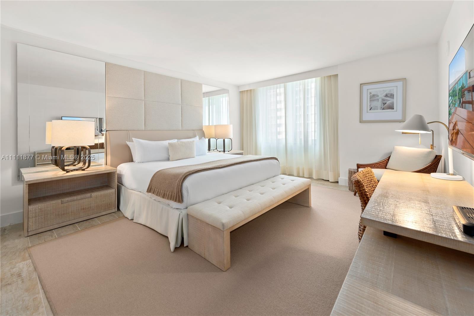 A bedroom features a king bed, upholstered headboard, desk, and large mirror in a neutral palette — 102 24th St # 915, Miami Beach FL 33139, MIAMI BEACH, FL