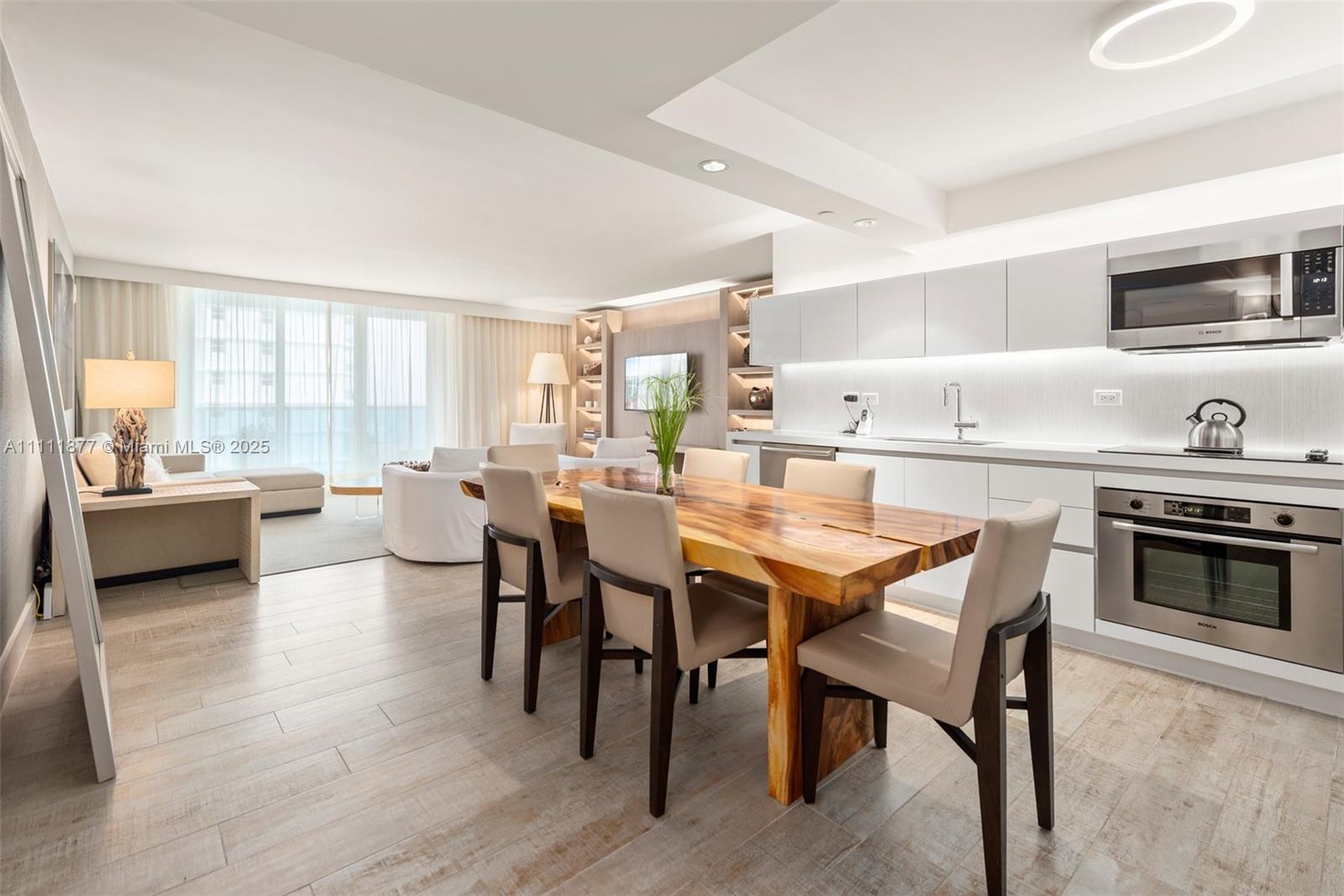 An open-concept living and dining area features a live-edge wood table and modern kitchen — 102 24th St # 915, Miami Beach FL 33139, MIAMI BEACH, FL