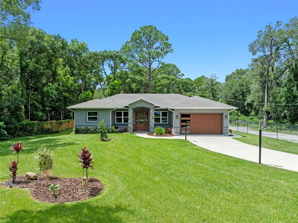 A single-story house with a gray exterior, stone accents, and a two-car garage — 308 CHURCH STREET, LAKE HELEN, FL