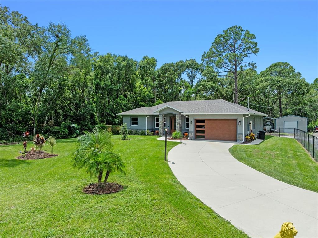 A single-story house with a gray exterior, stone accents, and a curved concrete driveway — 308 CHURCH STREET, LAKE HELEN, FL