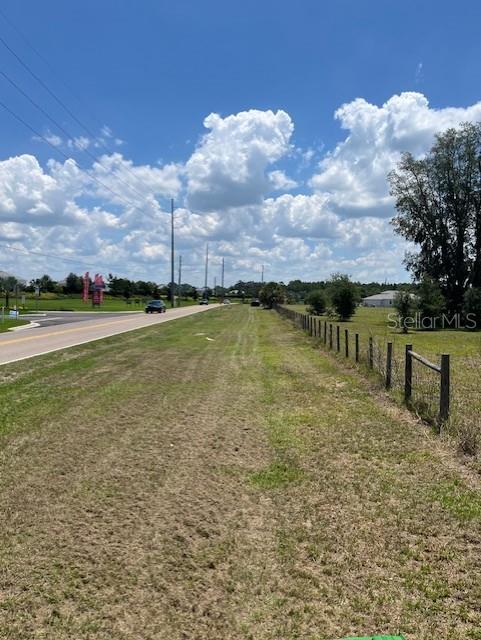 A grassy roadside lot borders a paved road and a wire fence under a cloudy sky — 15110 PATTERSON ROAD, ODESSA, FL