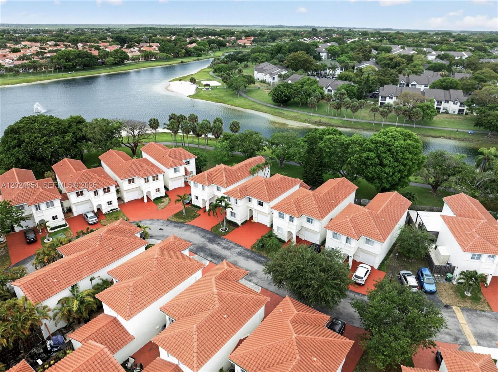 An aerial view shows a residential neighborhood with white townhouses featuring orange tile roofs — 14930 SW 104th St # 27, Miami FL 33196, MIAMI, FL