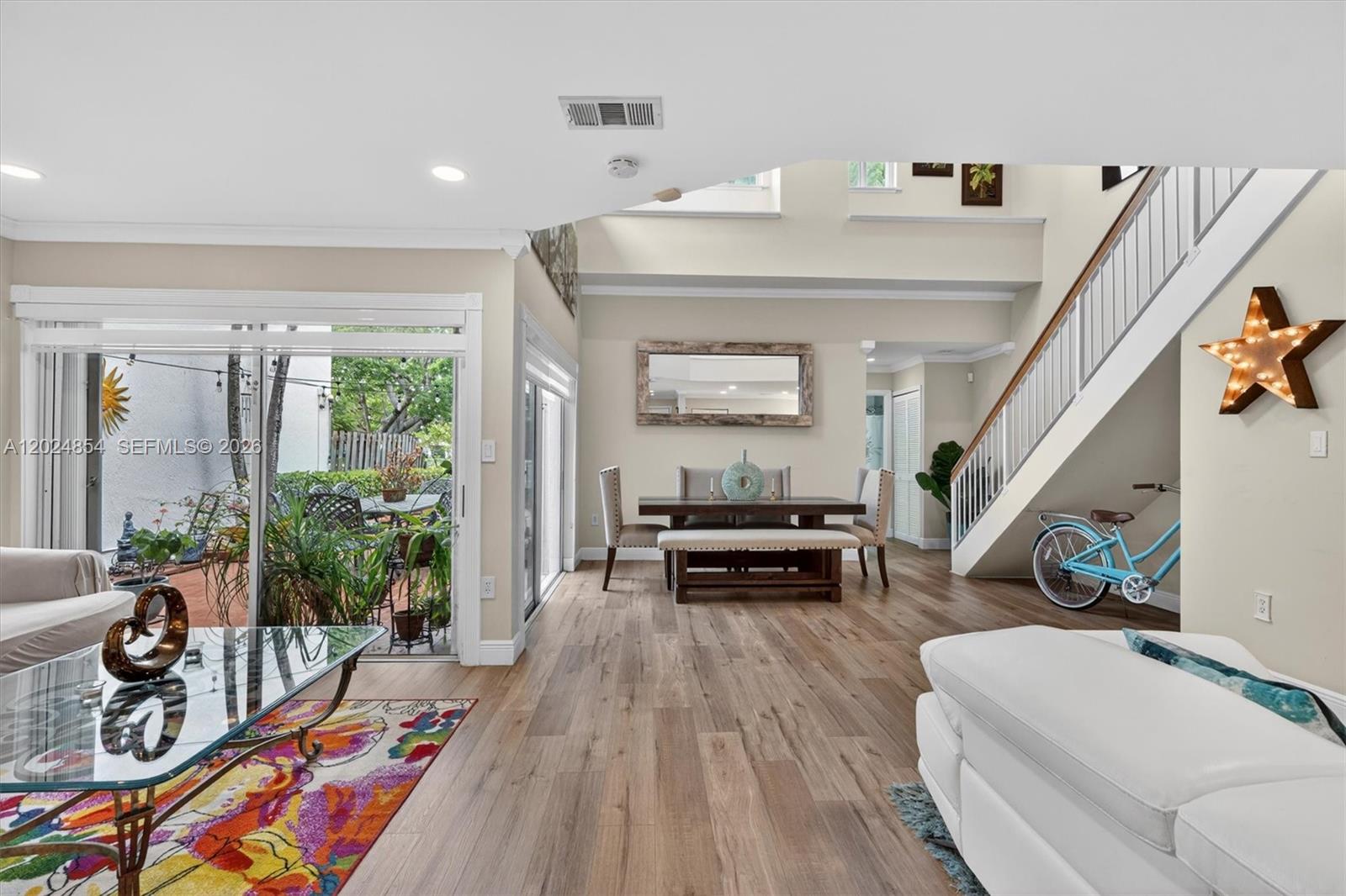 A living and dining area features wood-look flooring, a staircase, and a sliding glass door — 14930 SW 104th St # 27, Miami FL 33196, MIAMI, FL