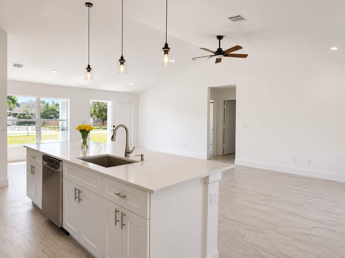 A bright, open-concept kitchen and living area features white cabinetry, a breakfast bar, and tile flooring — 9165 100th Ct, Vero Beach FL 32967, VERO BEACH, FL