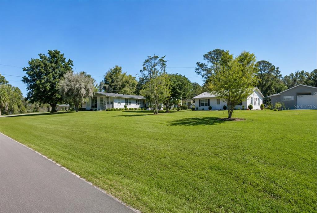A paved road leads to a large grassy lawn with two white houses and trees — NW 177TH PLACE, HIGH SPRINGS, FL