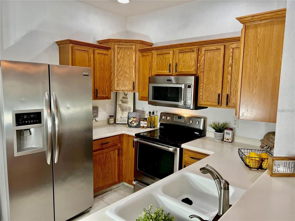 A kitchen features wood cabinets, stainless steel appliances, white countertops, and a double-basin sink — 3762 PARKRIDGE CIRCLE UNIT 23-106, SARASOTA, FL