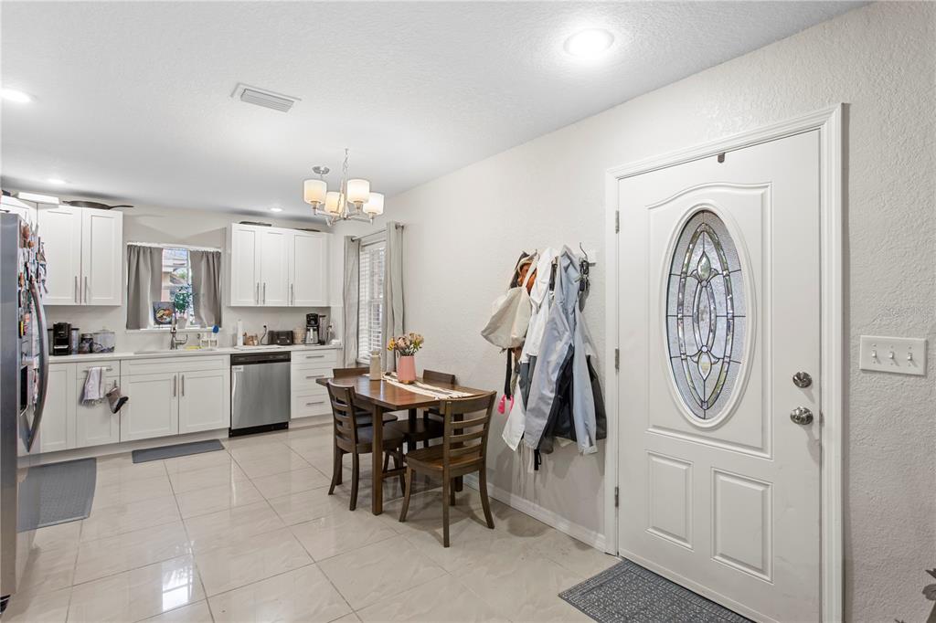A kitchen and dining area features white cabinets, stainless steel appliances, and a front door — 4215 W BAY VISTA AVENUE, TAMPA, FL