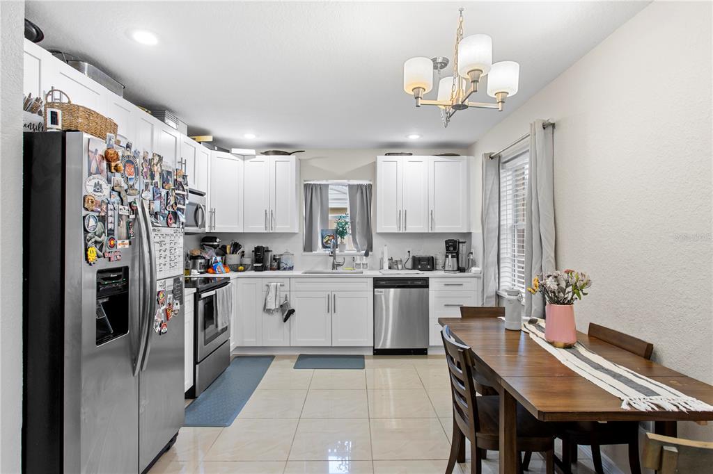 A kitchen with white cabinets, stainless steel appliances, and an adjacent wooden dining table — 4215 W BAY VISTA AVENUE, TAMPA, FL