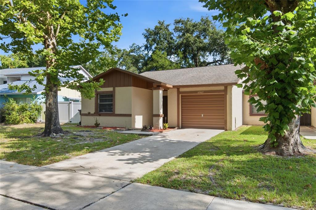 A single-story house with a tan stucco exterior, brown trim, and a one-car garage — 5967 FISH COURT, ORLANDO, FL