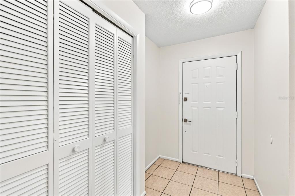 An entryway features a white louvered closet door, a white front door, and tiled flooring — 5967 FISH COURT, ORLANDO, FL