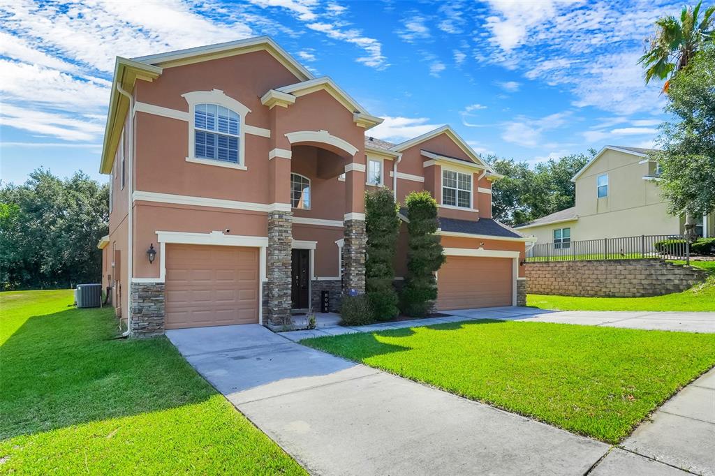 A two-story house with a tan stucco exterior, stone accents, and two attached garages — 11045 LEMAY DRIVE, CLERMONT, FL