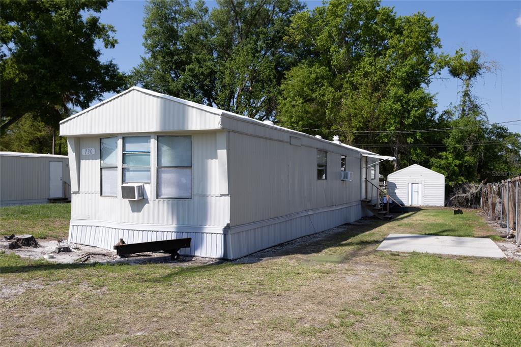 A white mobile home sits on a grassy lot with a small detached shed nearby — 728 N CHESTNUT ROAD, LAKELAND, FL