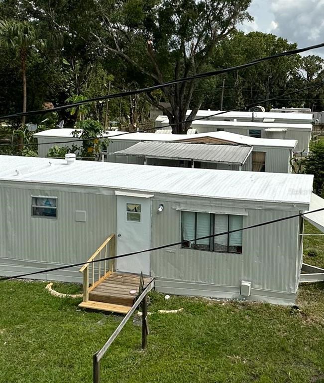 A white mobile home with a small shed and a tree stump in the yard — 728 N CHESTNUT ROAD, LAKELAND, FL