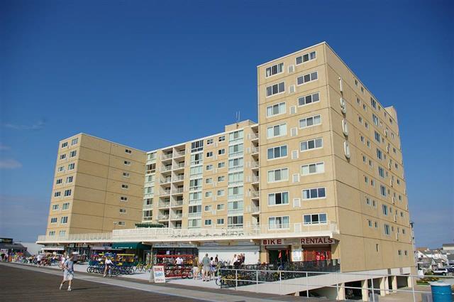 A multi-story tan apartment building with ground-level retail shops sits along a wooden boardwalk — 1904 Boardwalk, NJ, NJ