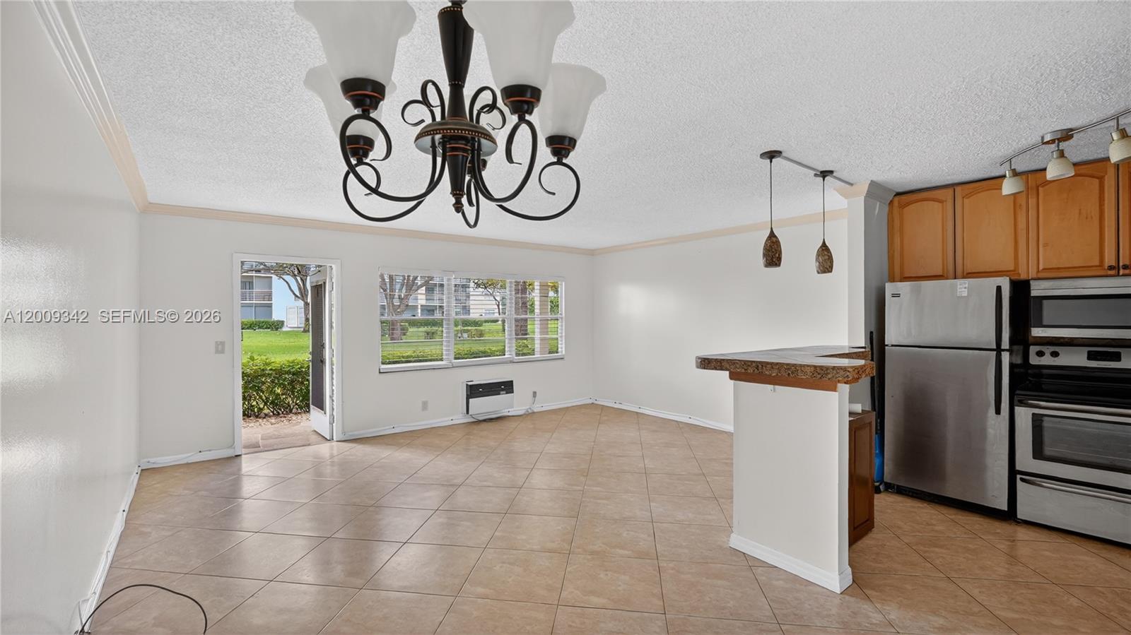 An open-concept living and kitchen area features tile flooring, a chandelier, and stainless steel appliances — 48 Mansfield B # 48, Boca Raton FL 33434, BOCA RATON, FL