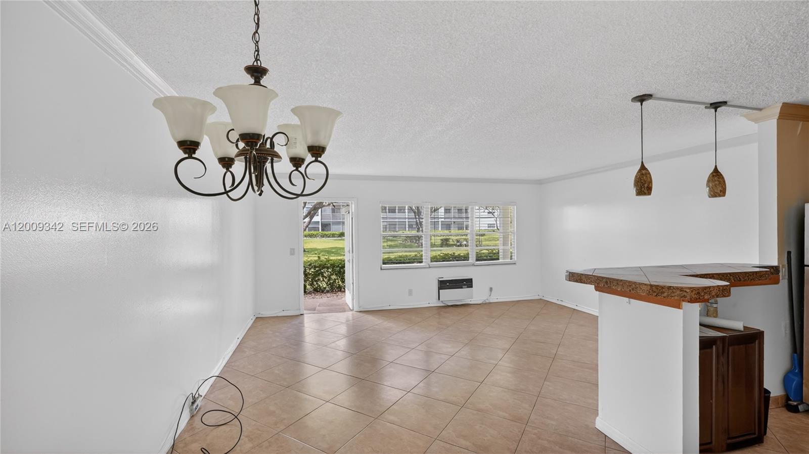 An open living area features tile flooring, a chandelier, pendant lights, and a glass door — 48 Mansfield B # 48, Boca Raton FL 33434, BOCA RATON, FL