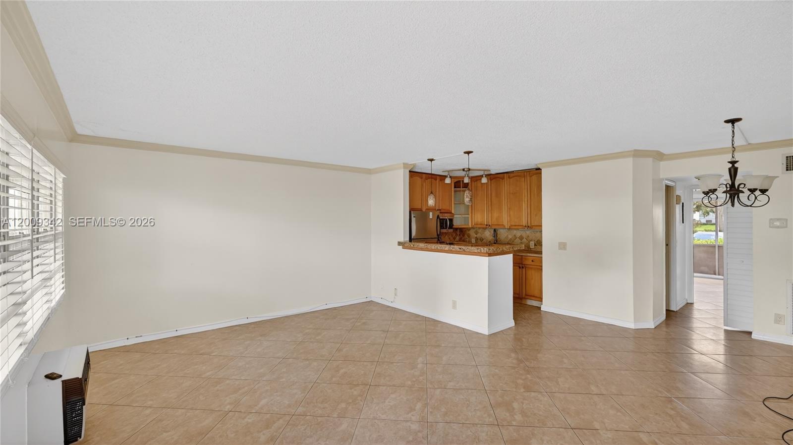 An open-concept living area features tile flooring, a kitchen with wood cabinets, and a breakfast bar — 48 Mansfield B # 48, Boca Raton FL 33434, BOCA RATON, FL