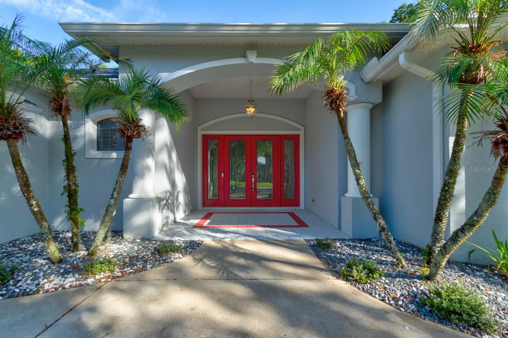 The front entrance of a house features a red double door under a covered porch — 1321 WICKLOW LANE, ORMOND BEACH, FL